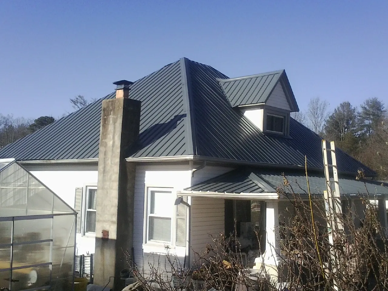 Dark blue standing seam metal roof on a white farmhouse with dormer — Slate & Tile Roof Repair by Roofing Brothers in Wenatchee