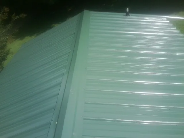 New green metal panels meeting at the ridge of a roof — Flat Roof Repair work by our crew in Wenatchee
