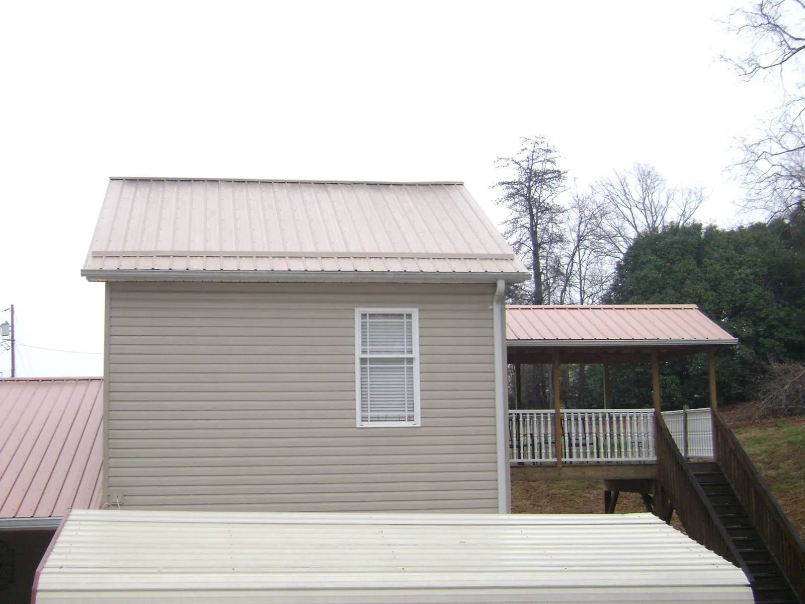 Tan metal roofs on a two story addition and attached porch, from a Roof Replacement job in Wenatchee