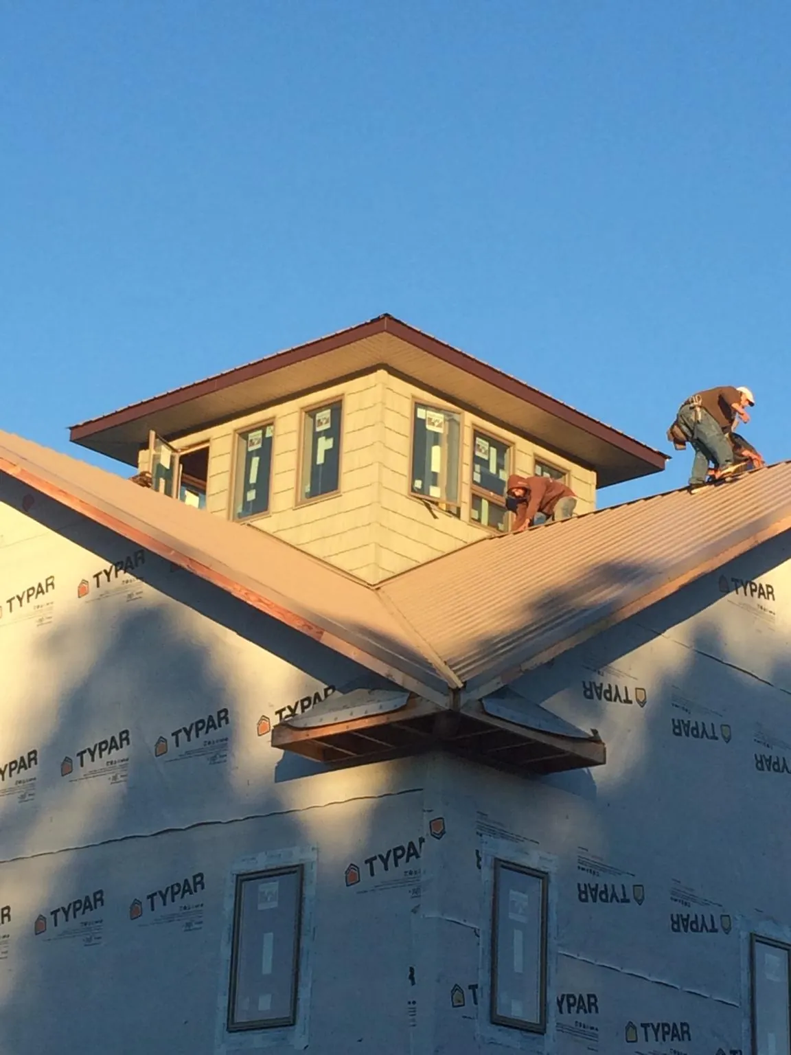 Roofers working around a rooftop cupola on a new metal roof at sunset — Roof Waterproofing in Wenatchee by Roofing Brothers